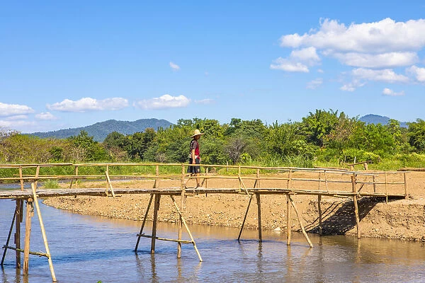 A man crossing a bridge over a river in Pai, Mae Hong Son province, Northern Thailand