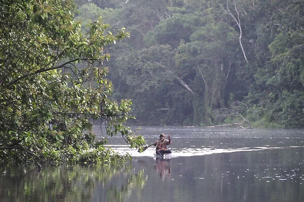 Man in a dugout canoe on the Amazon River, near Puerto Narino, Colombia