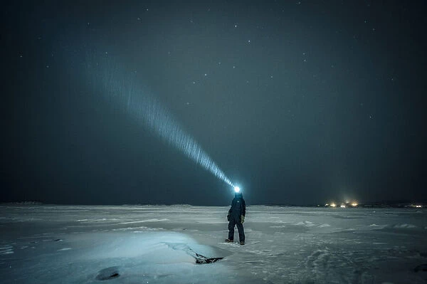 Man exploring the sky at night on a iced lake on the arctic circle, Abisko, Sweden