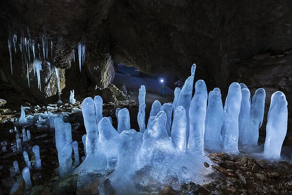 A man at Grotta dei Pagani with illuminated stalactites and stalagmites during night, Castione della Pesolana, Prealpi Orobie, Bergamo, Lombardy, Italy (MR)