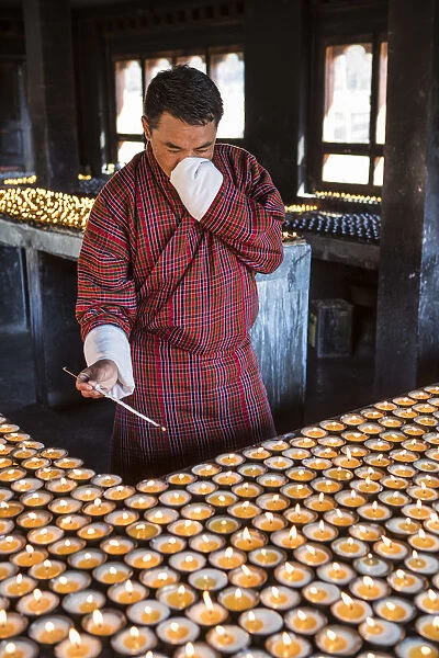 A man lighting candles in a shrine in Jambey Lhakhang, Jakar, Bumthang District, Bhutan