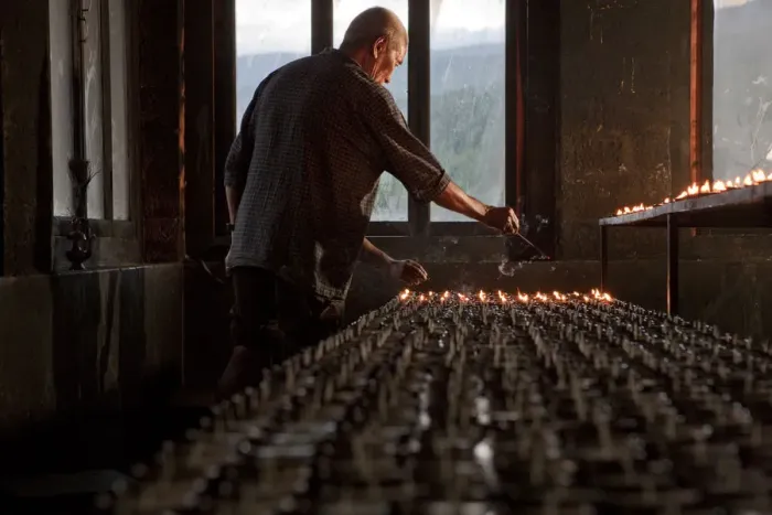 Framed Print : A man lighting candles in a temple in Bhutan Framed Print : A man lighting candles in a temple in Bhutan