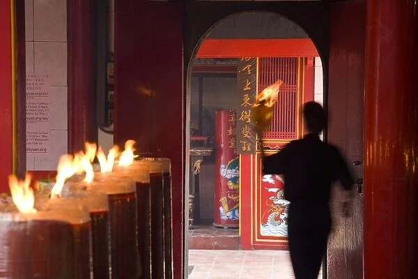 Man with lit paper in Chinese temple