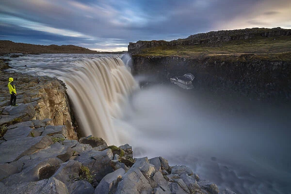 A man observes Dettifoss waterfall at its east side during midnight sun