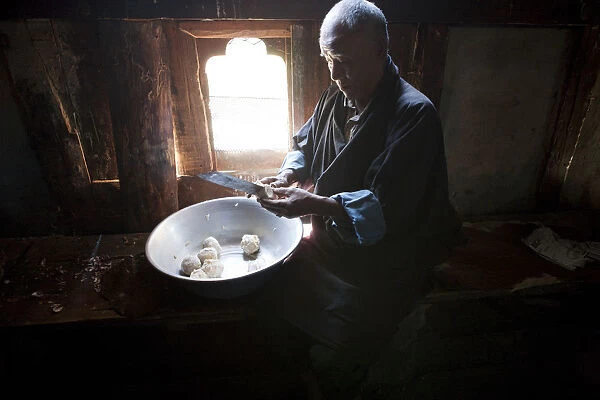 A man preparing potatos in the manufacture of arra in Ura in the Bumthang, Valley