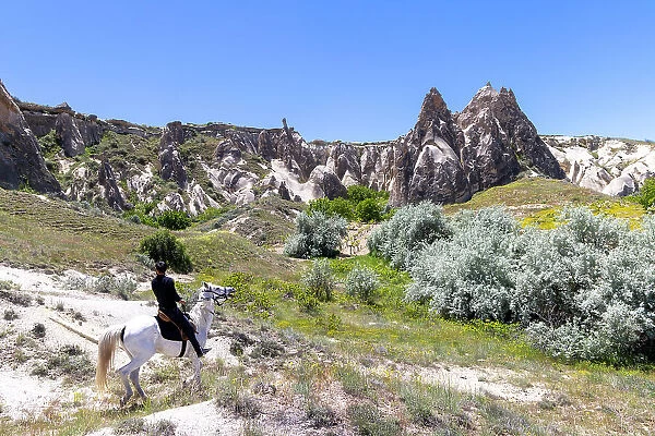 A man rides a horses through Cappadocia, Nevsehir Province, Central Anatolia, Turkey