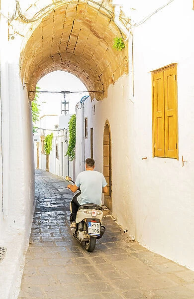 A man on a scooter in Lindos, Rhodes, Dodecanese Islands, Greece