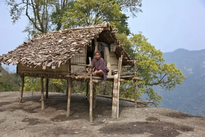 Framed Print : A man sits on the veranda of his small house, raised on stilts, situated precariously on the edge of a Framed Print : A man sits on the veranda of his small house, raised on stilts, situated precariously on the edge of a