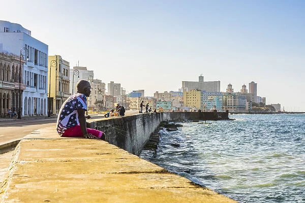 A man sitting and watching the ocean from the Malecon, La Habana Vieja (Old Town), Havana