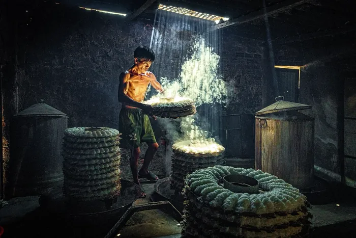 Framed Print : Man steaming traditional rice cakes in an old kitchen, Phan Thiet, Binh Thuan Province, Vietnam. (MR)