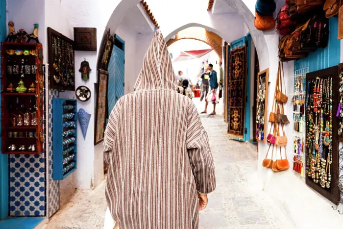 Framed Print : Man with traditional Djellaba looking at the gift shops in the street markets of Chefchaouen, Morocco