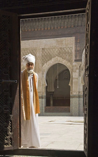 Man in traditional Moroccan clothing standing in doorway of Bou Inania Medersa, Fez