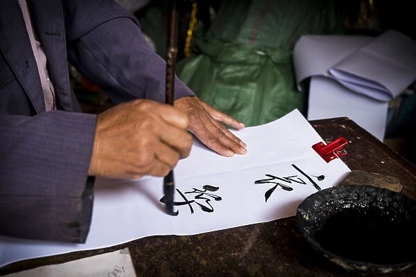 Man is writing with chinese idioms at Shigu Village or Stone Drum Village, Lijiang