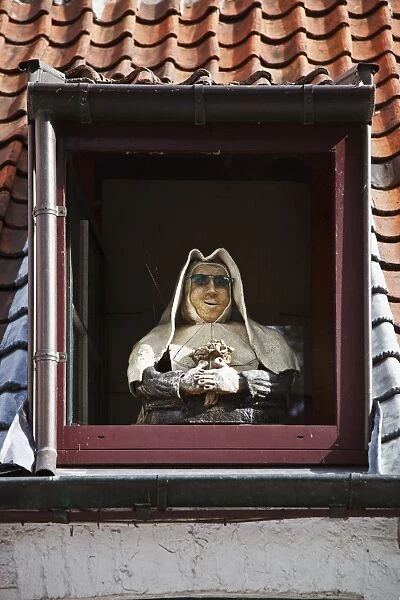 A mannequin nun stands in the dormwer window of a house in Brugge Sint Kruis