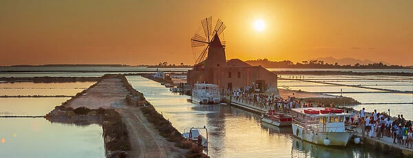 Marsala, Sicily. Tourists visiting the Marsala saltern at sunset with the windmill