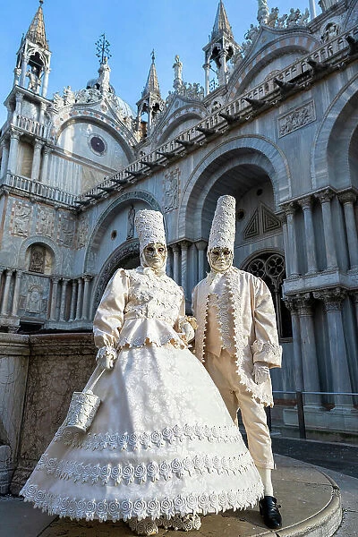 Masked couple posing in front of St Mark's Basilica during the carnival, Venice, Veneto, Italy