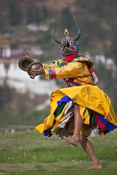 A masked dancer with cymbals performs Drametse Nga Cham (the religious masked dance)