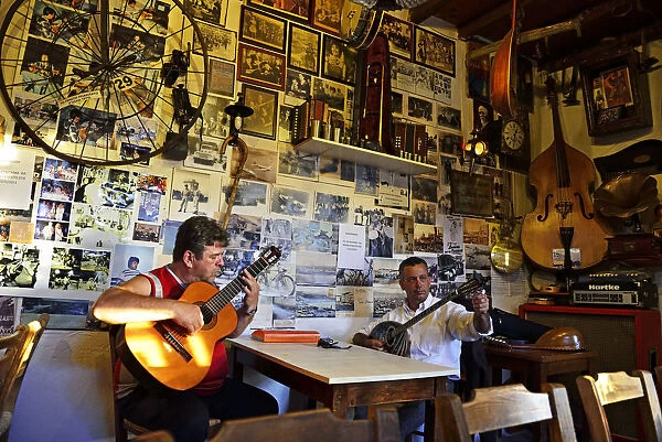 Men play musical instruments at a bar in Crete, Greece, Europe
