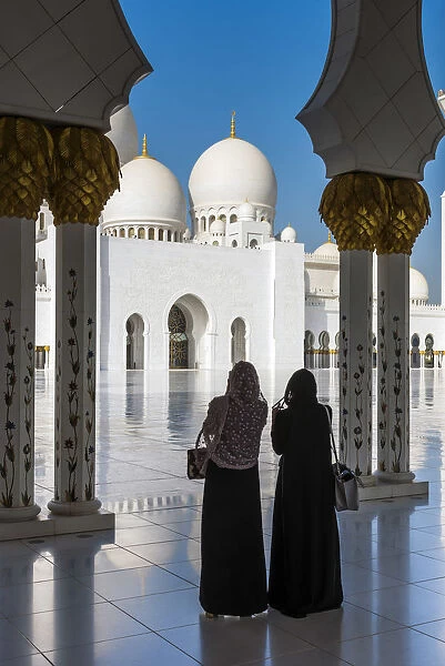 Two Middle Eastern women traditionally dressed watching the Sheikh Zayed Mosque, Abu