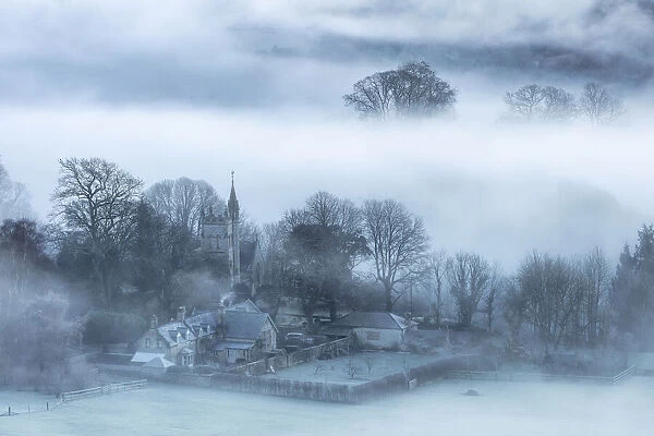 Mist around Melbury Abbas church from Melbury Hill, Cranborne Chase, Dorset, England, UK