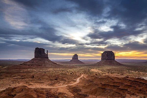 The Mittens against cloudy sky at sunrise, Monument Valley, Arizona, USA