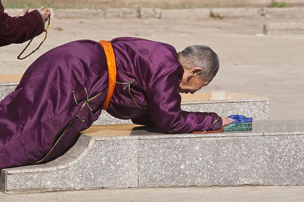 MONGOLIA, Ulaanbaatar, Monk prostrating at Gandan (Gandantegchenling) Monastery