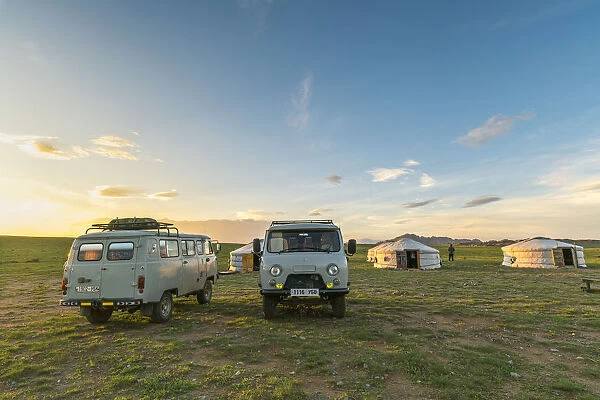 Mongolian nomadic traditional gers and soviet minivans at sunset. Middle Gobi province