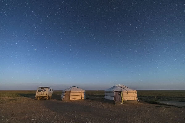 Mongolian traditional gers and soviet minivan under a starry sky