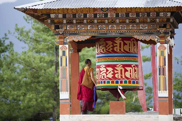 A monk and a prayer wheel on the path to the Paro Taktsang monastary in the Himalayan