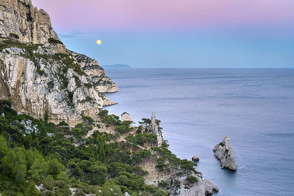 Full moon rising over ocean and Mediterranean landscape at Calanque de Sugiton after