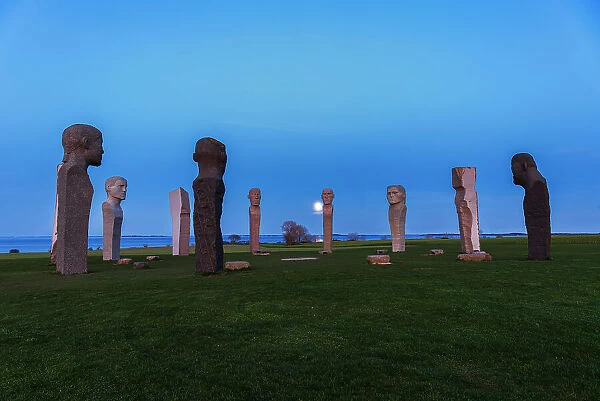 Full moon rising behind the stone statues of Dodekalitten at dusk, Lolland island, Zealand, Denmark