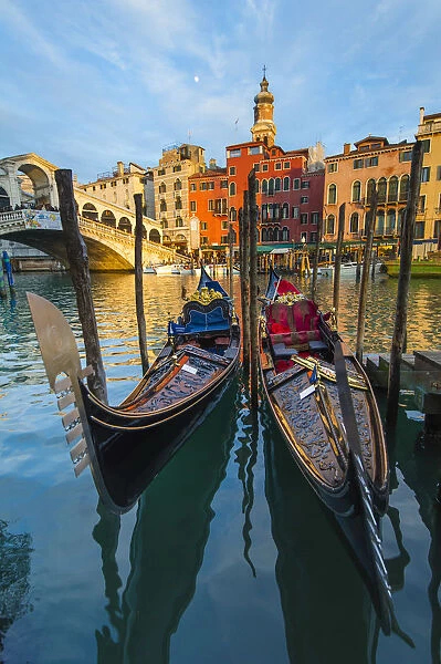 Moored gondolas in front of the Rialto bridge at sunset. Venice, Veneto, Italy