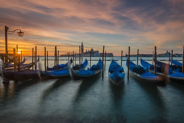 Moored gondolas at sunrise with San Giorgio Maggiore island in the background, Venice