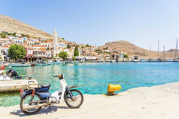 Motor cycle by the harbour and St Nicholas Church, Halki, Dodecanese Islands, Greece