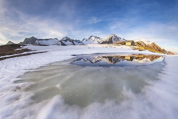 Mount Disgrazia and Corni Bruciati reflecting in the Lake Meltri in the thawing season