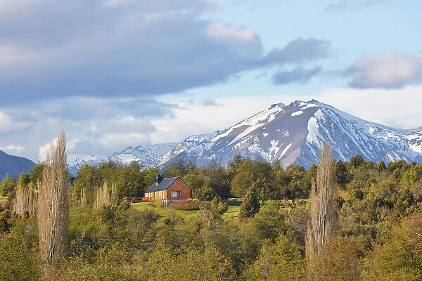 A mountain cabin with the Andes snowy peaks in background, near the Carrileufu River, Cholila, Chubut, Patagonia, Argentina