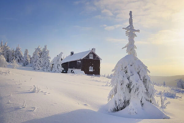 mountain cottage in deep snow-covered winter landscape at Fichtelberg at sunset