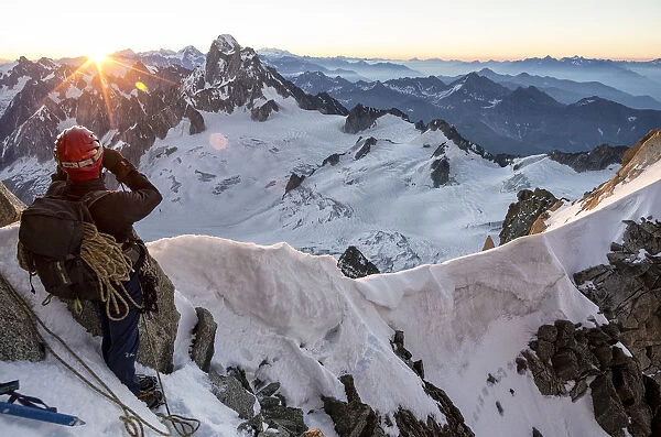 Mountaineer looks at Dent du Geant from Col du Diable at dawn before climbing Arete