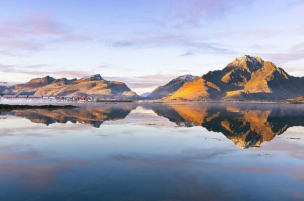 Mountains and rorbuer reflected in a Fjord during sunset, Leknes, Vestvagoy, Nordland, Lofoten Islands, Norway