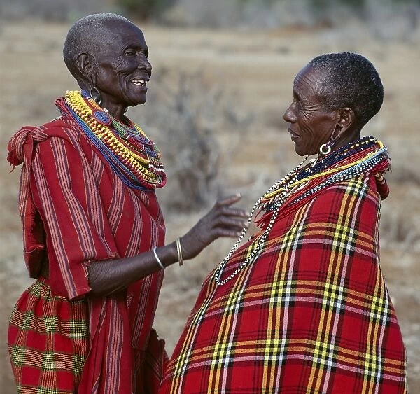 Two Msai women in traditional attire chat to each other