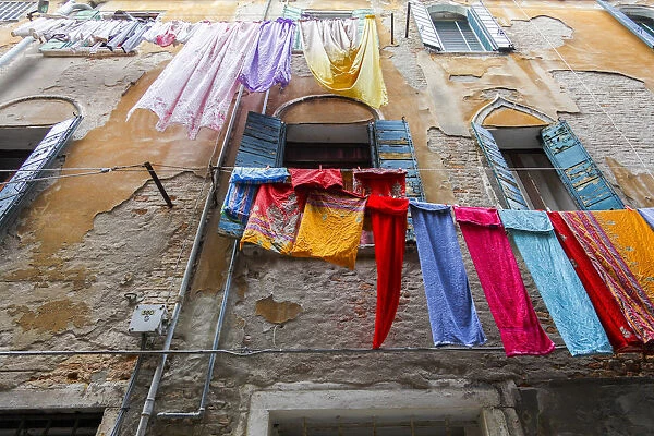 Multicolored laundry hangs in front of an old facade, Venice, Veneto, Italy