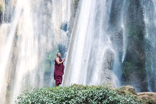 Myanmar, Mandalay division, Pyin Oo Lwin. Burmese monk praying under Dattawgyaik Waterfall