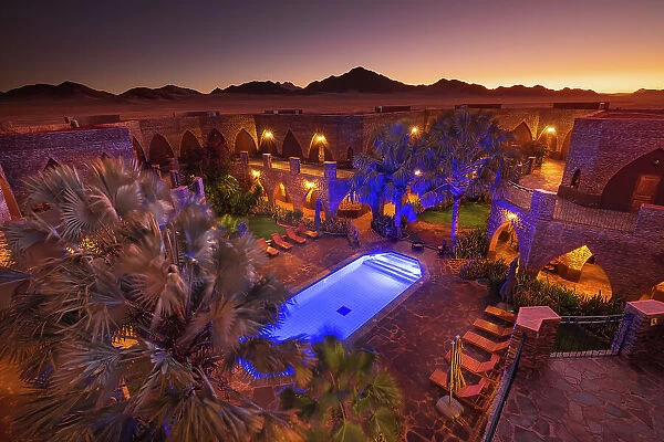 Namibia, a swimming pool in a luxury hotel in the Namib Naukluft National Park with the sun setting on the Namib desert dunes