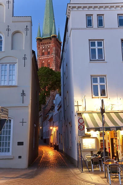 Narrow street to St Petri Church & cafe restaurant at dusk, Lubeck, Germany