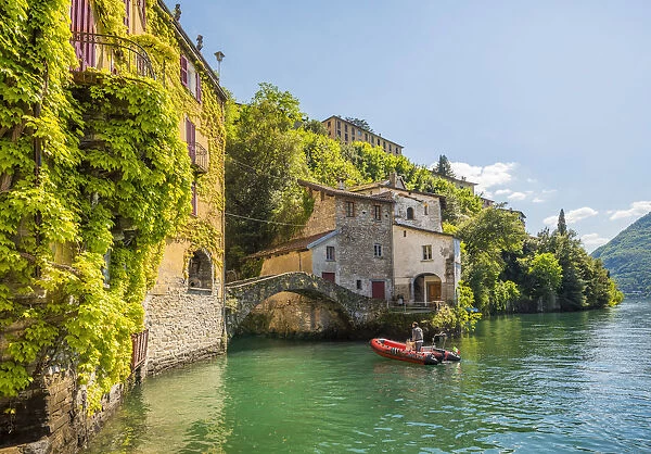 Nesso, lake Como, Como province, Italy. A small boat approaching the roman stone bridge