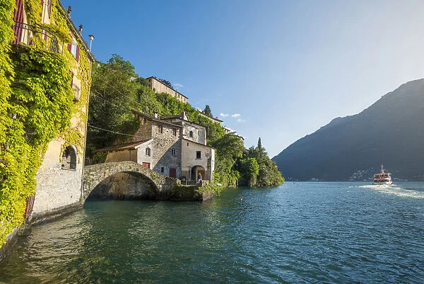 Nesso, lake Como, Como province, Italy. The roman stone bridge and a tourist boat