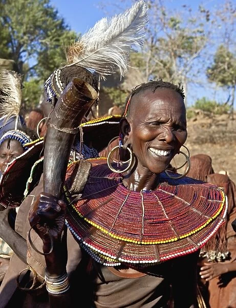 During a Ngetunogh ceremony, the mother of a Pokot initiate sings and dances holding high the cowhorn container she used to smear fat over the masks of her son and other boys as