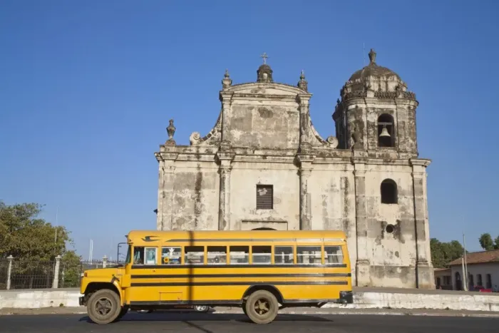Framed Print : Nicaragua, Leon, American yellow bluebird bus driving past San Juan Church Framed Print : Nicaragua, Leon, American yellow bluebird bus driving past San Juan Church