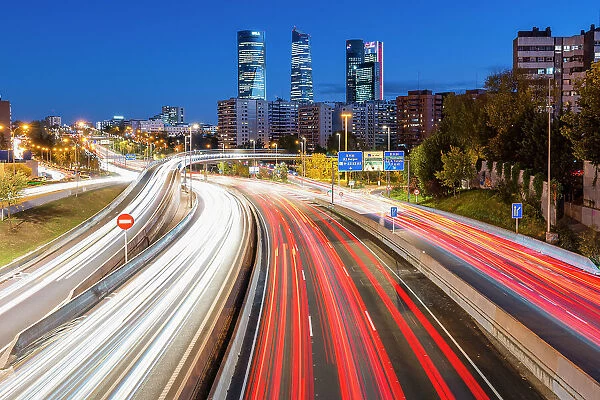 Night view of car light trails on an urban highway with Four Towers (Cuatro Torres) business district in the background, Madrid, Spain