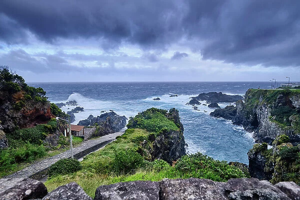 The northeast coast of Flores island, at Boqueirao, on a stormy day. The ramp to pull the sperm whales on the left, by the sea. Azores islands, Portugal